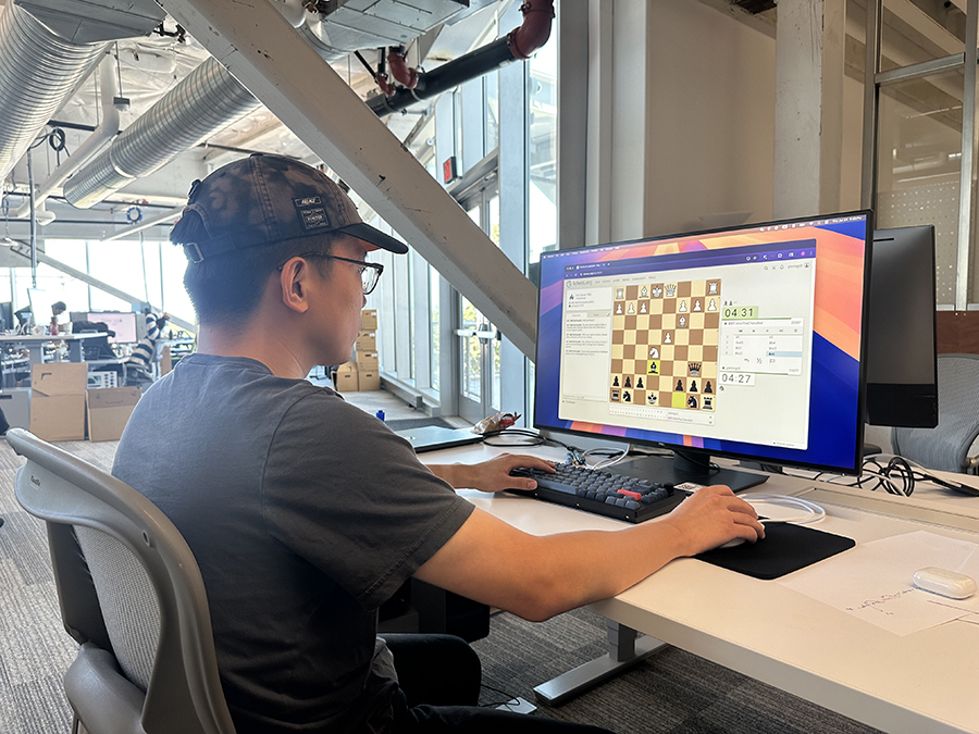 LTI Ph.D. student Yiming Zhang sits at a computer with a chessboard visible on the monitor