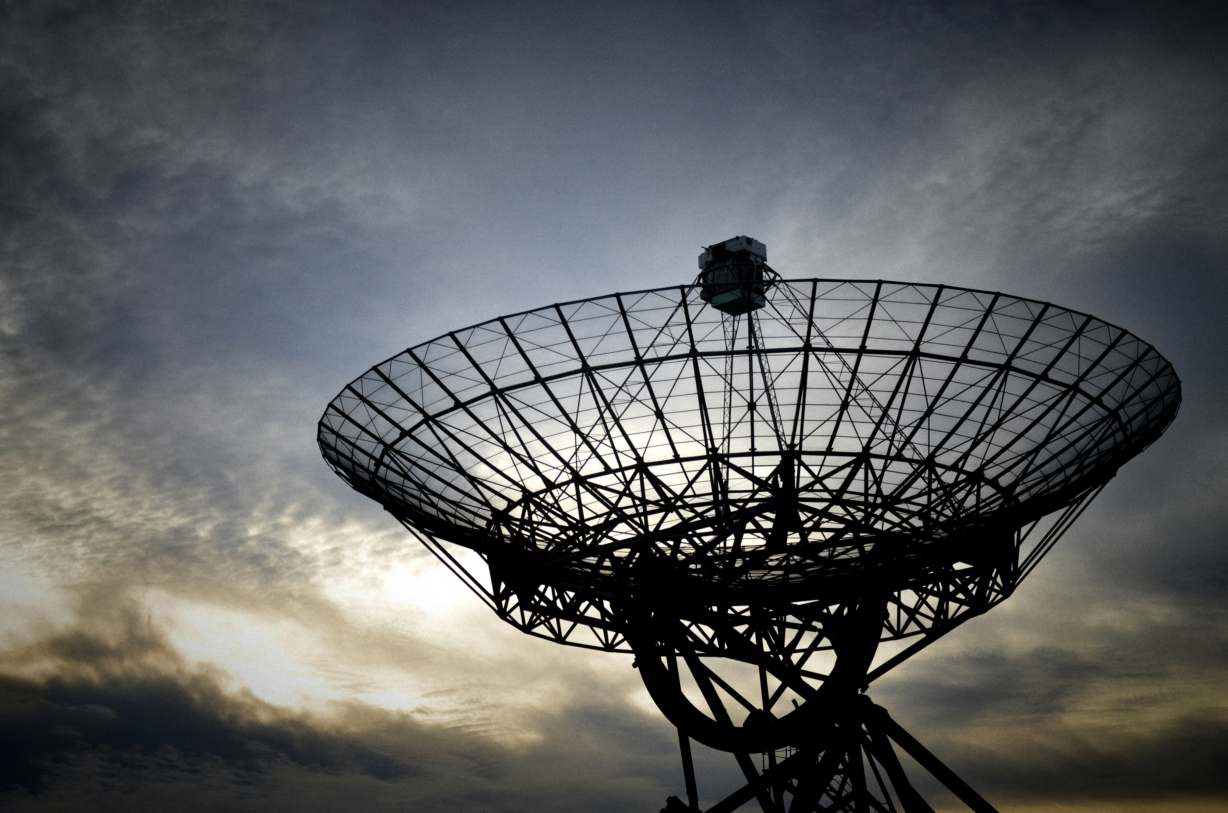 Photo of a large satellite dish in front of a cloudy evening sky