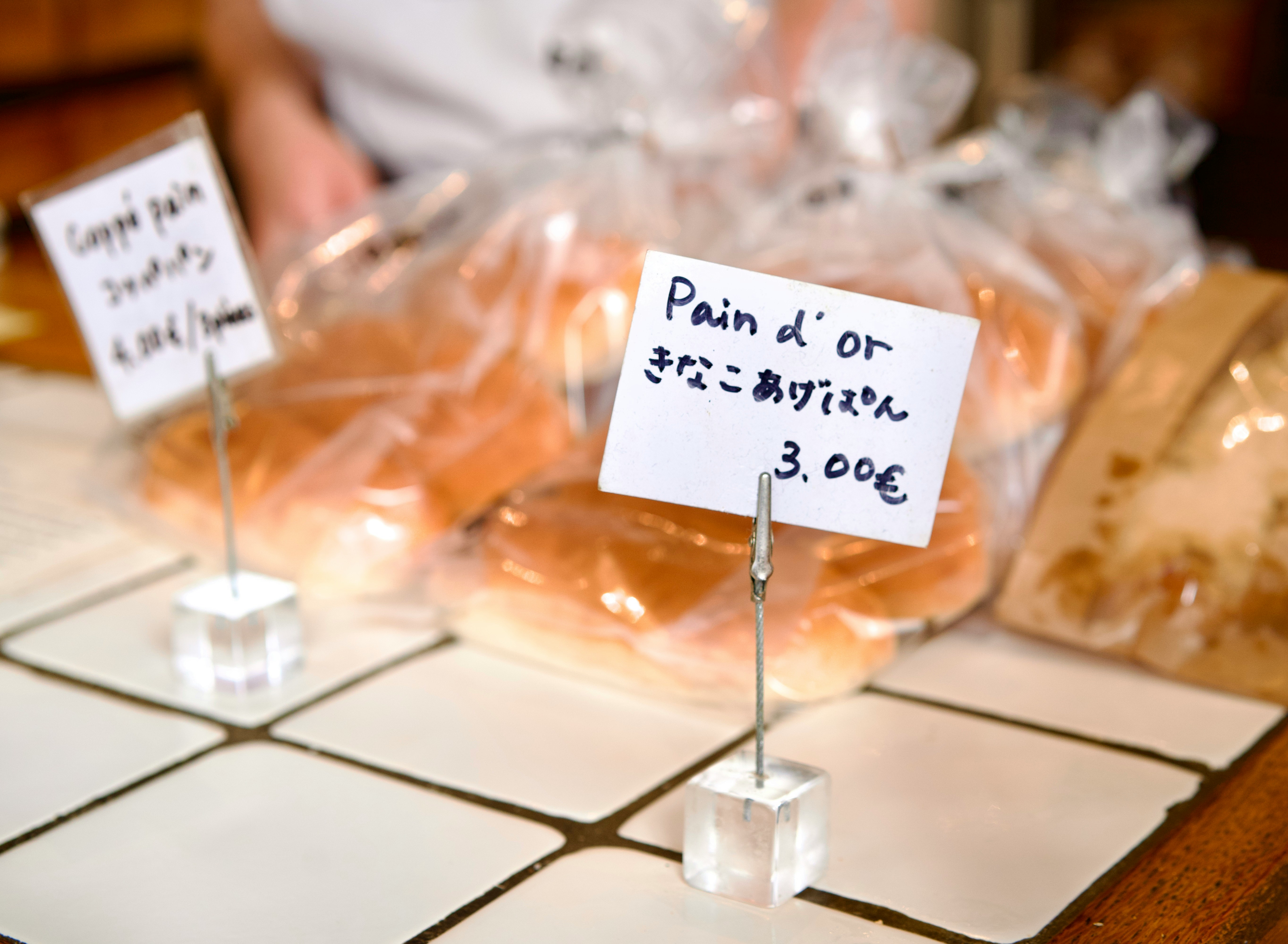 A photo of signs indicating the name and price of baked goods in multiple languages